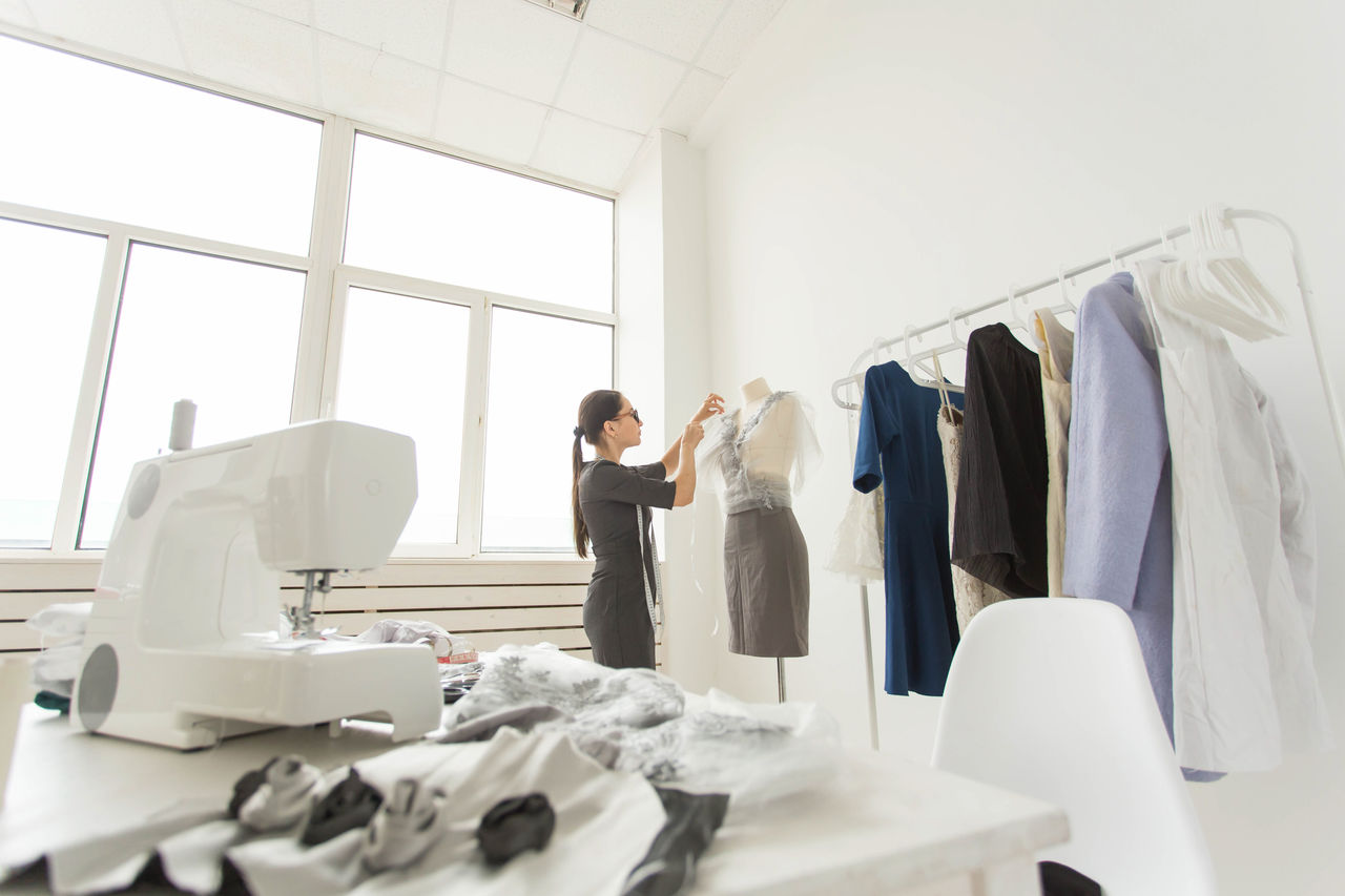 people, fashion and showroom concept - young fashion designer in her showroom.